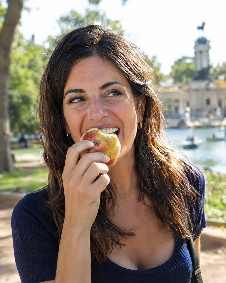 Mujer riendo mientras muerde una manzana