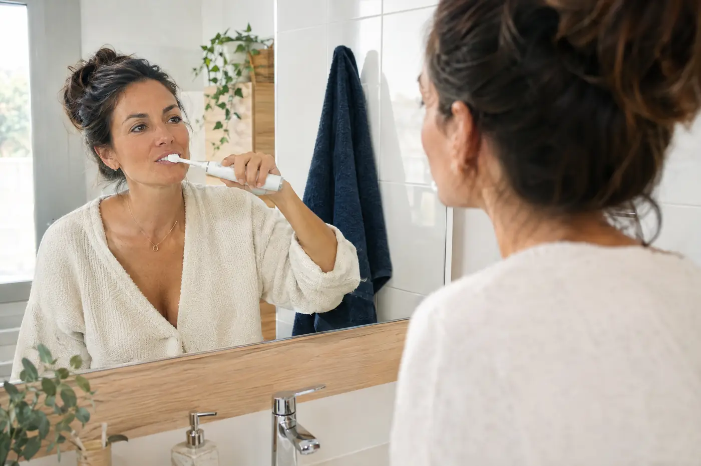 Mujer cepillándose los dientes con cepillo eléctrico
