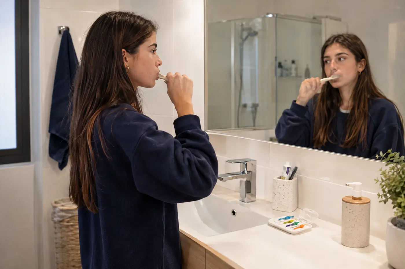 Chica cepillándose los dientes con cuidado ante el espejo